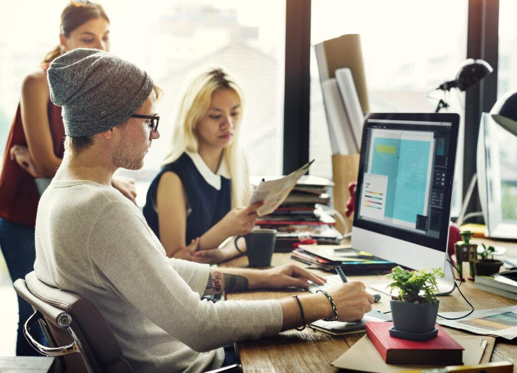 Web designer in Durango, CO, taking detailed notes on a custom website development project in a professional office setting.